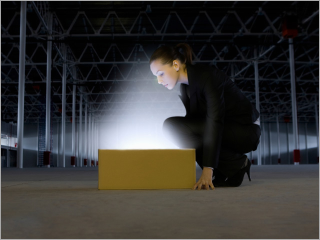 Businesswoman Looking At Glowing Box In Empty Warehouse